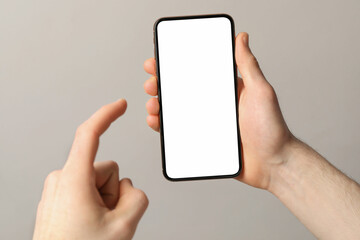 Man holding smartphone with blank screen on light grey background, closeup. Mockup for design