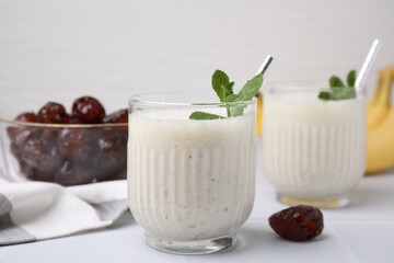 Glasses of delicious date smoothie with mint on white table