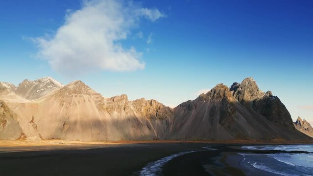 Drone shot of vestrahorn mountains in iceland, stokksnes beach peninsula creating majestic icelandic scenery. Beautiful nordic landscape with black sand beach, scenic route. Slow motion.