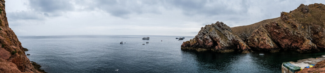 Fototapeta na wymiar Panoramic view of the coast of the Berlenga Islands in the Atlantic Ocean of Portugal. Cloudy landscape of the Iberian Peninsula. Fishing boats in the water.