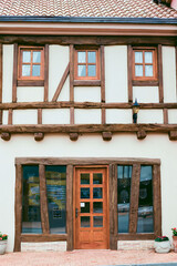 Front exterior of medieval European style house with door and glass windows. No people.