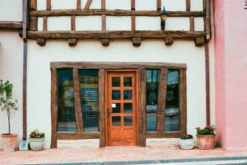 Front exterior of medieval European style house with door and glass windows. No people.