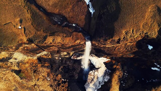 Aerial view of foss a sidu waterfall creating fantastic frozen landscape, icelandic scenery. Beautiful scandinavian cascade running down off of hills, scenic route. Slow motion.