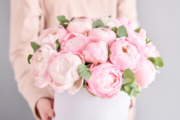 Fototapeta na wymiar A bouquet of pink peonies in women's hands. Flower delivery. A beautiful bouquet of flowers as a gift for a holiday.