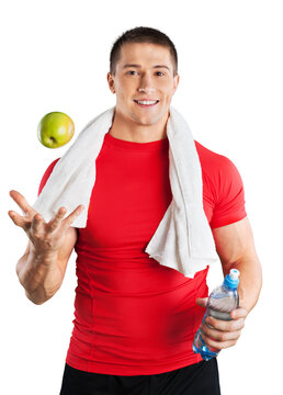 Handsome athletic man with the towel on neck throws an apple