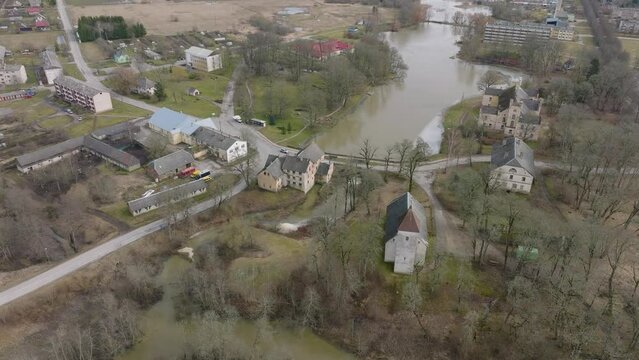 Aerial establishing view of high water in springtime, flood, Durbe river (Latvia), Cirava city, brown and muddy water, sunny day, wide drone shot moving forward tilt down