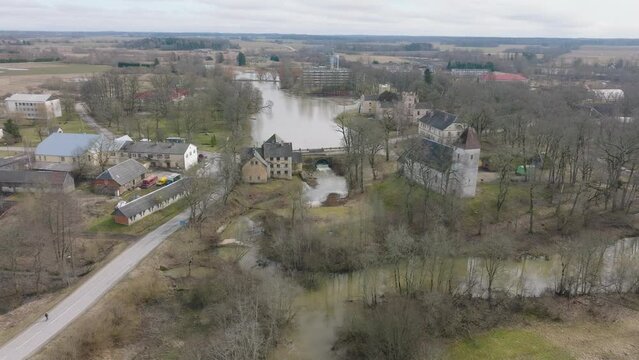 Aerial establishing view of high water in springtime, flood, Durbe river (Latvia), Cirava city, brown and muddy water, sunny day, wide drone shot moving forward, tilt down