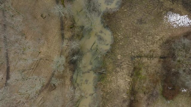 Aerial establishing view of high water in springtime, flood, Durbe river (Latvia), Cirava city, brown and muddy water, sunny day, birdseye drone shot moving forward