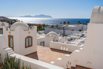 White wall buildings near Red sea on tropical beach on sunny day in resort town Sharm El Sheikh,...