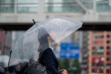 傘をさして雨の街を歩く女性の横顔