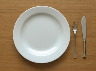 empty white plate on a wooden table with cutlery