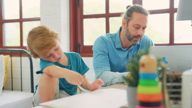Caucasian attractive father use laptop computer with young son beside.