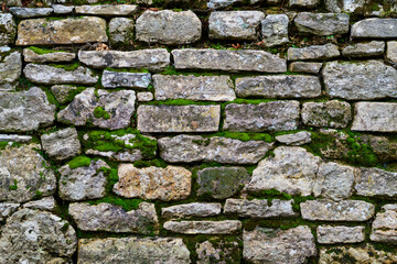 An ancient free stone wall with heavy rough texture and moss