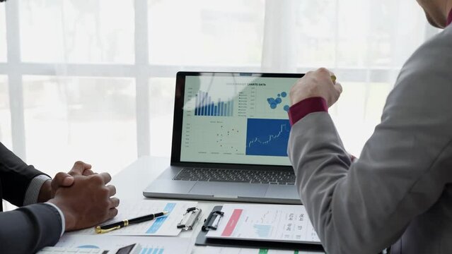 Asian businessmen and investors brainstorm applications for web design planning and develop templates, graphs, and calculations for mobile projects working together in the office.	
