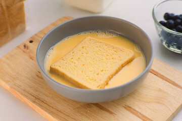 The process of dipping the bread in the egg to fry in the pan. Fried bread slices for breakfast.