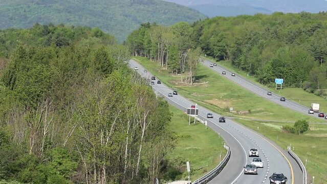 Cars drive on I89 in the mountains of Vermont.  A hilly interstate road.