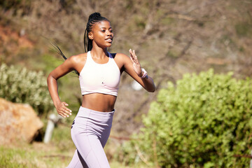 Fototapeta Black woman, mountain running and nature for fitness, speed or challenge for wellness with focus in summer. African girl, workout and runner training in sunshine with exercise, adventure and hiking obraz