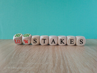 High or low stakes symbol. Concept words High stakes and Low stakes on wooden cubes. Beautiful wooden table blue background. Business high or low stakes concept. Copy space.