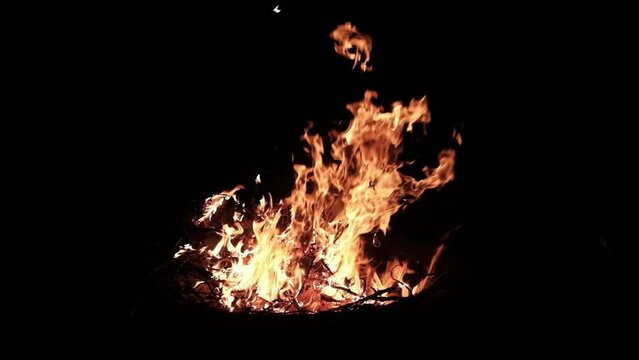 Slow motion of flames erupting while burning lot of dry wood in the fire pit at nigh.