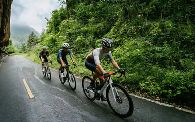 Groups of cyclists riding road bikes in the morning are climbing.
