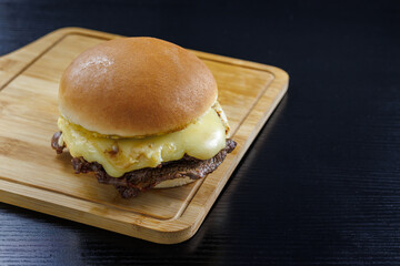 Barros Luco sandwich popular in Chile: beef with melted cheese. on black table and wooden board...