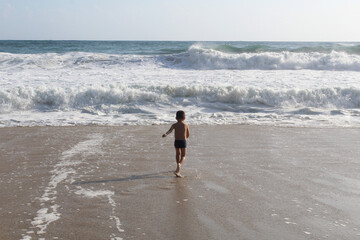 boy on the beach running on the waves of the sea