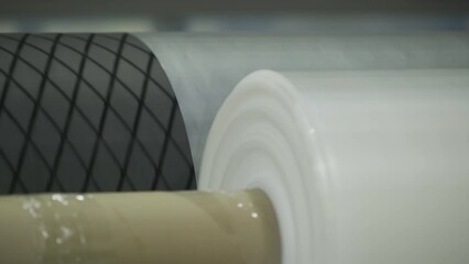 Factory machine processing plastic material on the production line. Machine processing plastic rolls on the conveyor belt. Industrial machine processing coils of plastic film material.