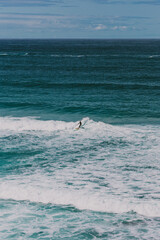 Wide vertical shot of a surfer riding the waves at Bondi Beach in Australia