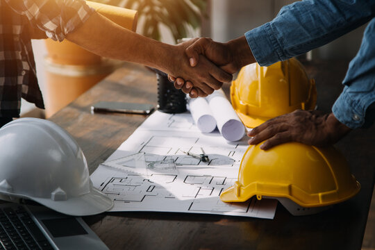 Three colleagues discussing data working and tablet, laptop with on on architectural project at construction site at desk in office