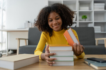 Young African American woman learning from a book. learning materials University study projects, attend online learning meetings, watch video lessons on the Internet, write notes.
