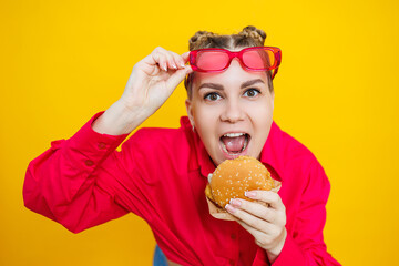 Close-up of a pregnant woman in a bright pink shirt and junk food. Hamburger and pregnancy. The...