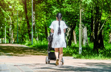 Mother wheeling a pram in the Park
