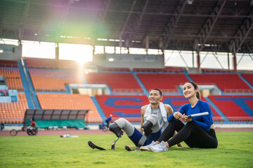 Asian para-athlete with prosthetic blades and trainer sit in stadium.  - Powered by Adobe