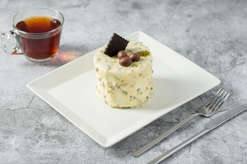 Single person mini cake with pistachio and white chocolate on a white porcelain plate