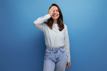 european young brunette female adult in a striped shirt and jeans with hair below her shoulders in a studio background