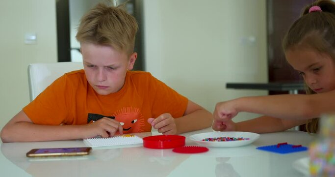 Children play with mosaic. Kid makes figure from bead 