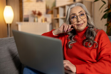 Long-haired pretty senior woman in eyeglasses with a laptop