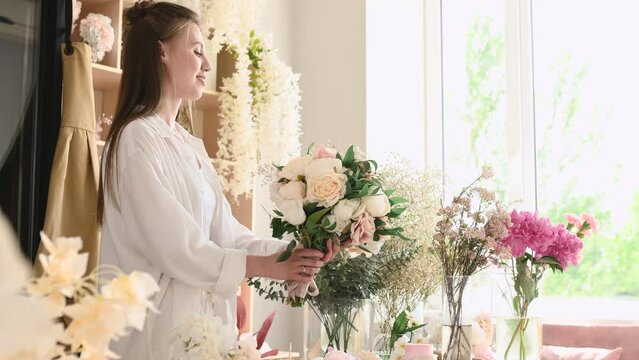 A young woman florist makes a wedding bouquet in her shop. Floral design studio, making decorations and arrangements. Flower delivery, order creation. Small business.