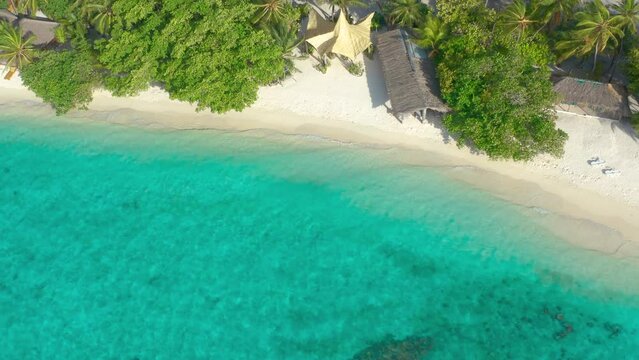 Aerial view on eco resort on a white sand beach with thatched huts and lush tropical vegetation on Bora Bora, French Polynesia.
