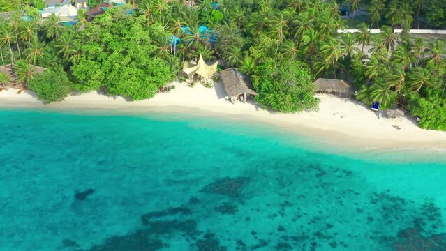 Aerial top view on white sand beach with thatched huts and lush tropical island Bora Bora, French Polynesia.