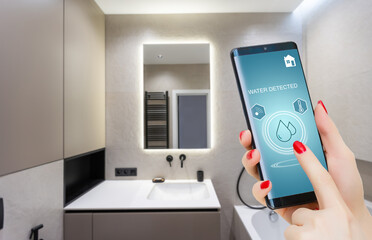 Hand holding smart phone with home control application with water detected, Smart home concept.