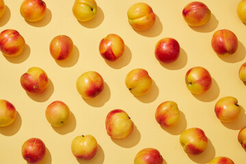 Colorful fruit pattern of fresh peaches (prunus persica) on yellow background. Creative background for advertising and branding for cosmetic or product with ingredient from peach
