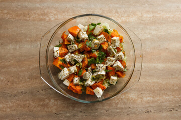 Salad with red pumpkin, cottage cheese, various vegetables and spices. Close-up