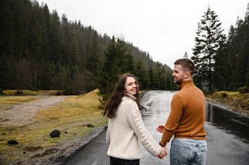 the couple is happy together. young woman and man hugging and glowing together in the rain on an asphalt road