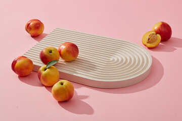Fresh fruit concept with several small peaches placed on the podium over a pink background. Thanks to vitamins A and C, Peach (Prunus persica) helps improve health