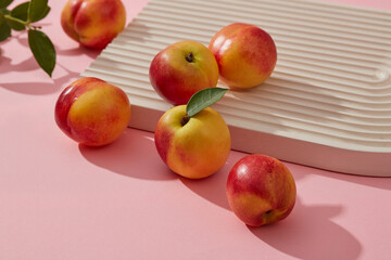 Close-up view of fresh peaches decorated on pattern podium with green leaves. Peach (Prunus persica) has many benefits for the skin because of their rich nutritional value