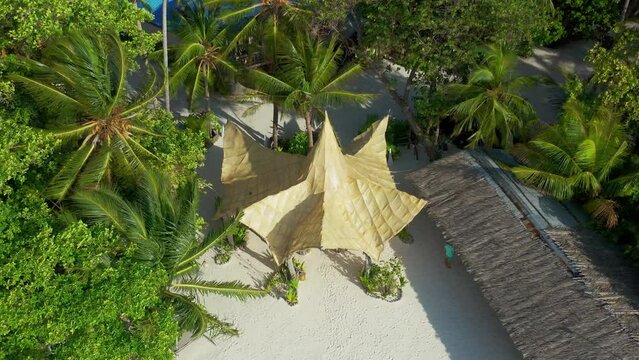 Aerial view bamboo bungalows with thatched on white sand beach and palm trees tropical island Bora Bora, French Polynesia.