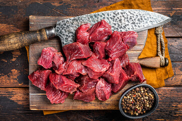 Sliced Raw venison dear meat for a stew, game meat on butcher cutting board. Wooden background. Top view - obrazy, fototapety, plakaty