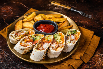 Chicken shawarma durum doner kebab with vegetable salad and french fries. Dark background. Top view