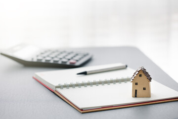 home model on notebook with pen and calculator
